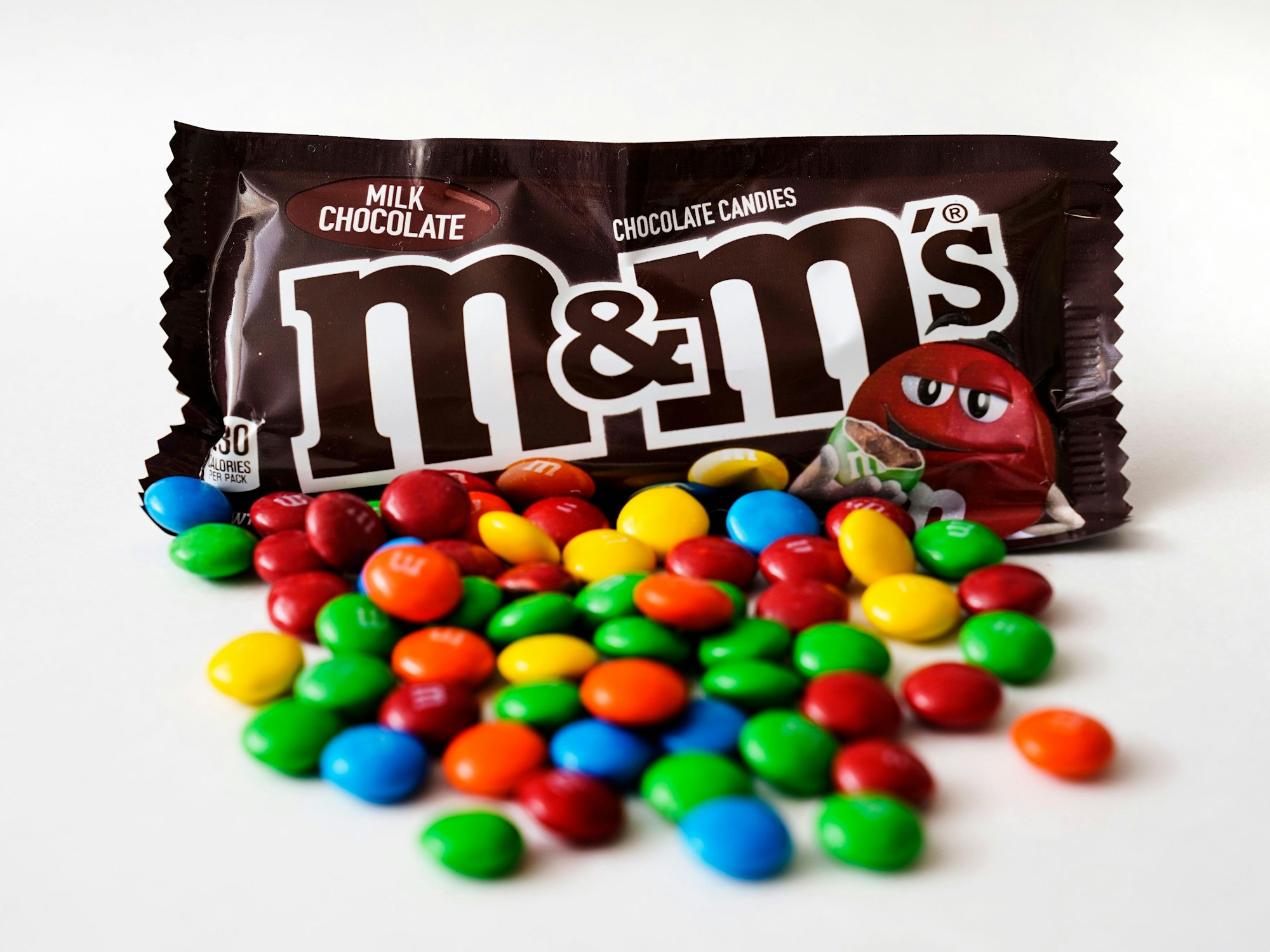 M&M's liegen vor einer Packung der Schokolinsen.