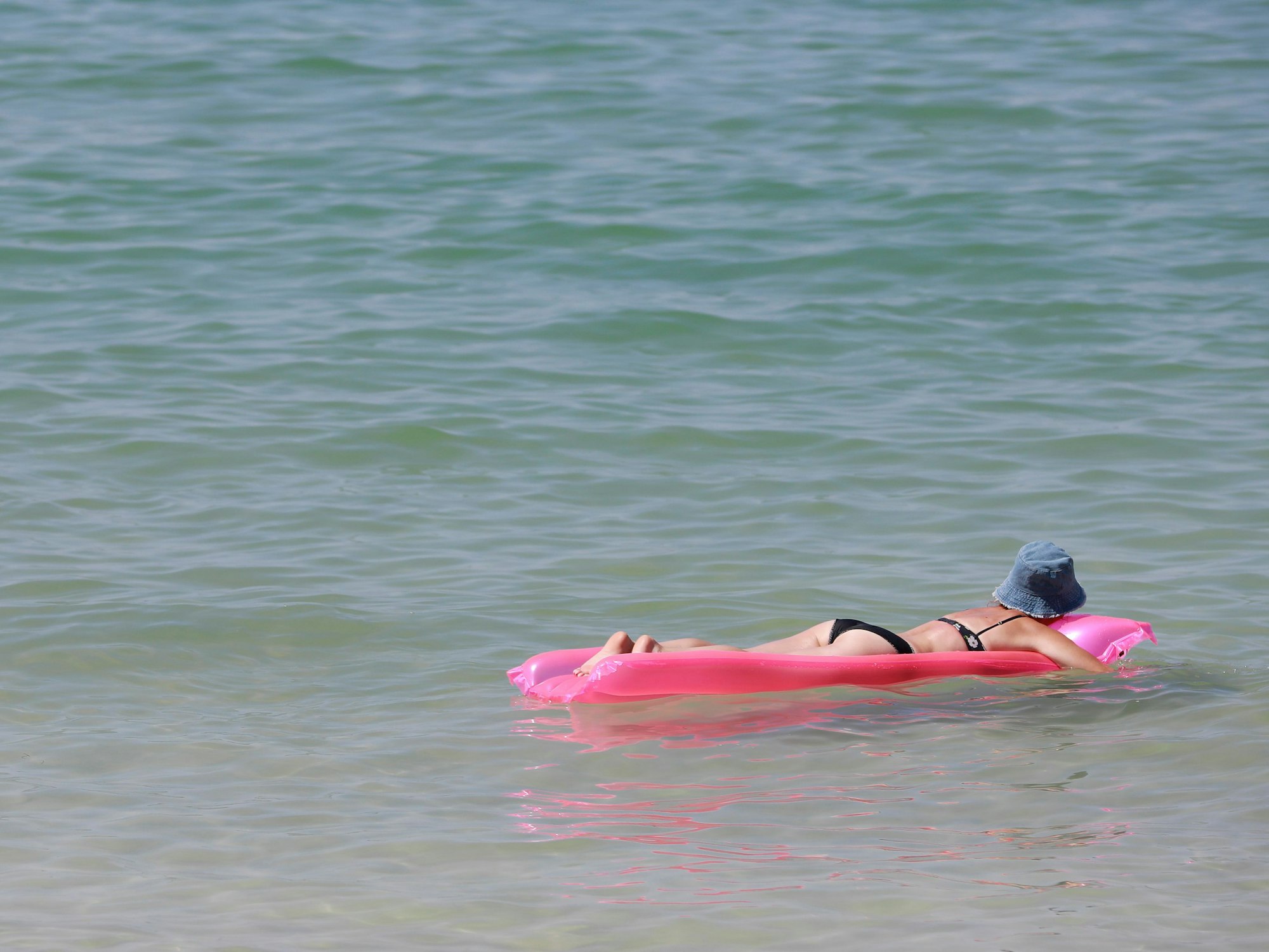 Eine Frau ruht sich auf einer Luftmatratze im Mittelmeer aus.