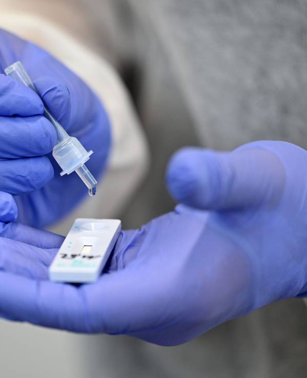 Ein Helfer verarbeitet eine Probe für einen Corona-Schnelltest. Ab dem 1. Februar müssen Corona-Infizierte in NRW nicht mehr in häusliche Isolation.