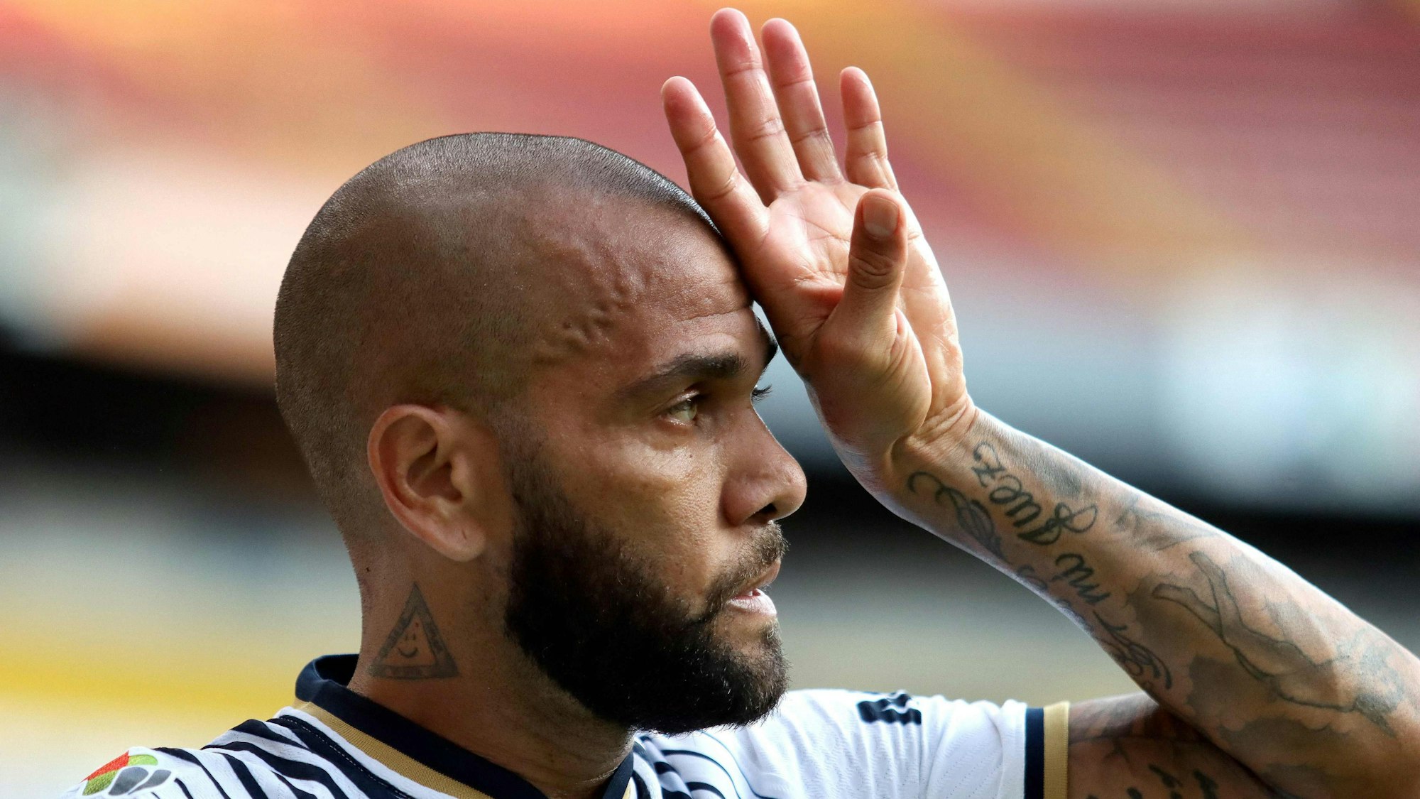 Dani Alves hält sich bei einem Fußballspil die linke Hand vors Gesicht.