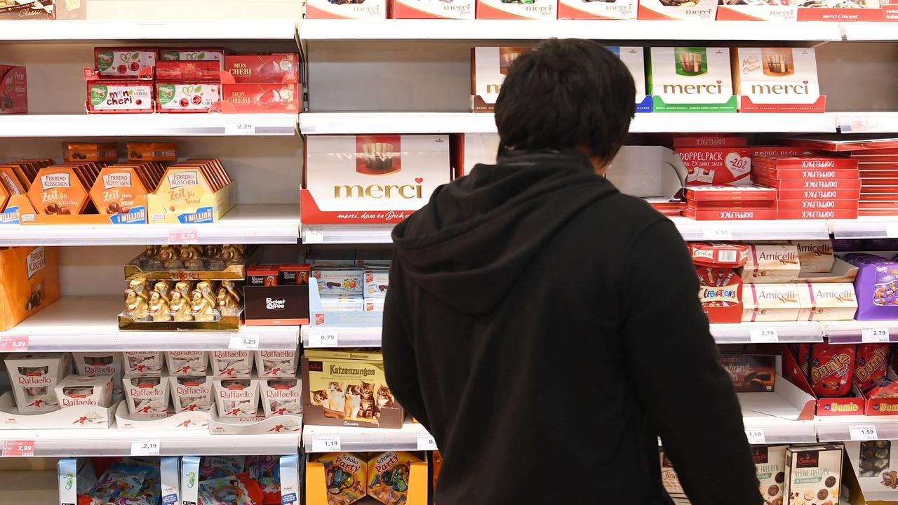 Ein Kunde steht vor einem Süßigkeiten-Regal im Supermarkt.