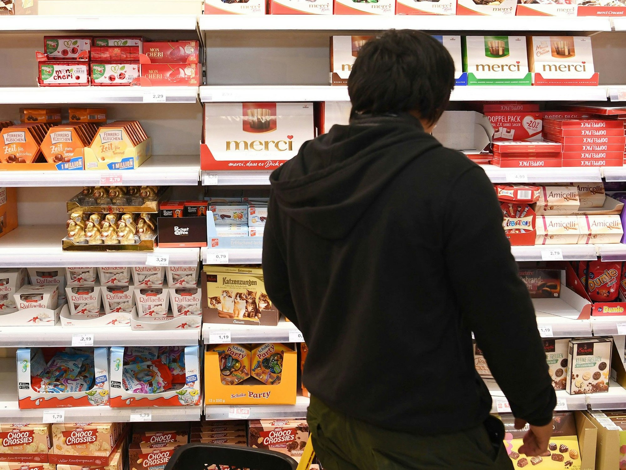 Ein Kunde steht vor einem Süßigkeiten-Regal im Supermarkt.