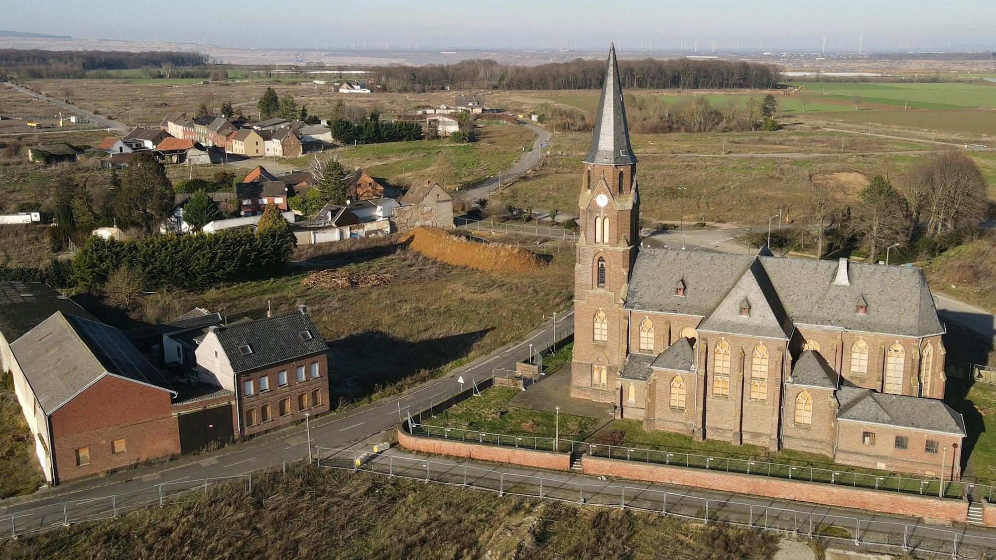 Wie ein Mahnmal ragt die entweihte Kirche St. Albanus und Leonhardus in Manheim-alt in den Himmel. Im Hintergrund naht der Tagebau Hambach.