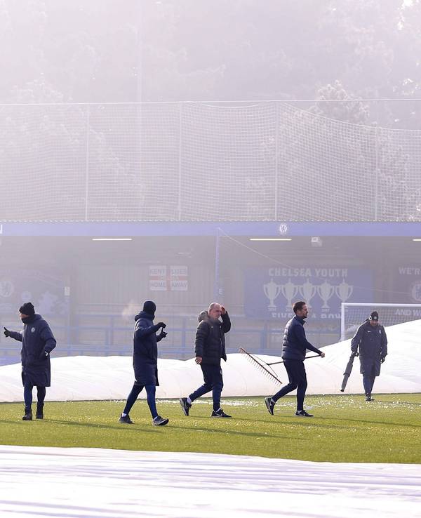 Zahlreiche Helfer versuchen vergeblich, den teils abgedeckten Platz im Stadion der Frauen des FC Chelsea bespielbar zu machen.