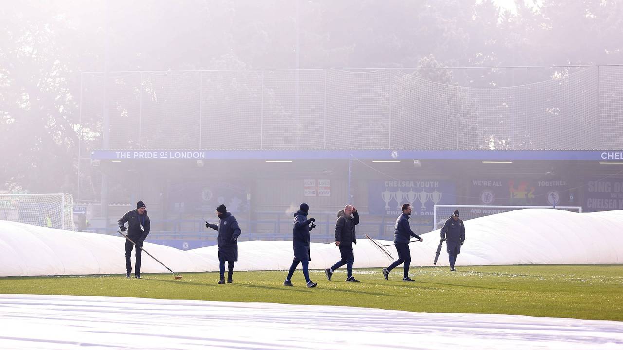 Zahlreiche Helfer versuchen vergeblich, den teils abgedeckten Platz im Stadion der Frauen des FC Chelsea bespielbar zu machen.