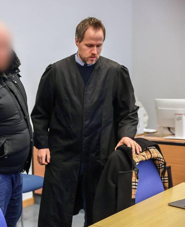 Der Angeklagte (M) steht im Gerichtssaal neben seinem Verteidiger Ingmar Rosentreter (r). Der Mann steh wegen Beteiligung an den Krawallen beim Conference-League-Spiel des 1. FC Köln in Nizza vor Gericht.