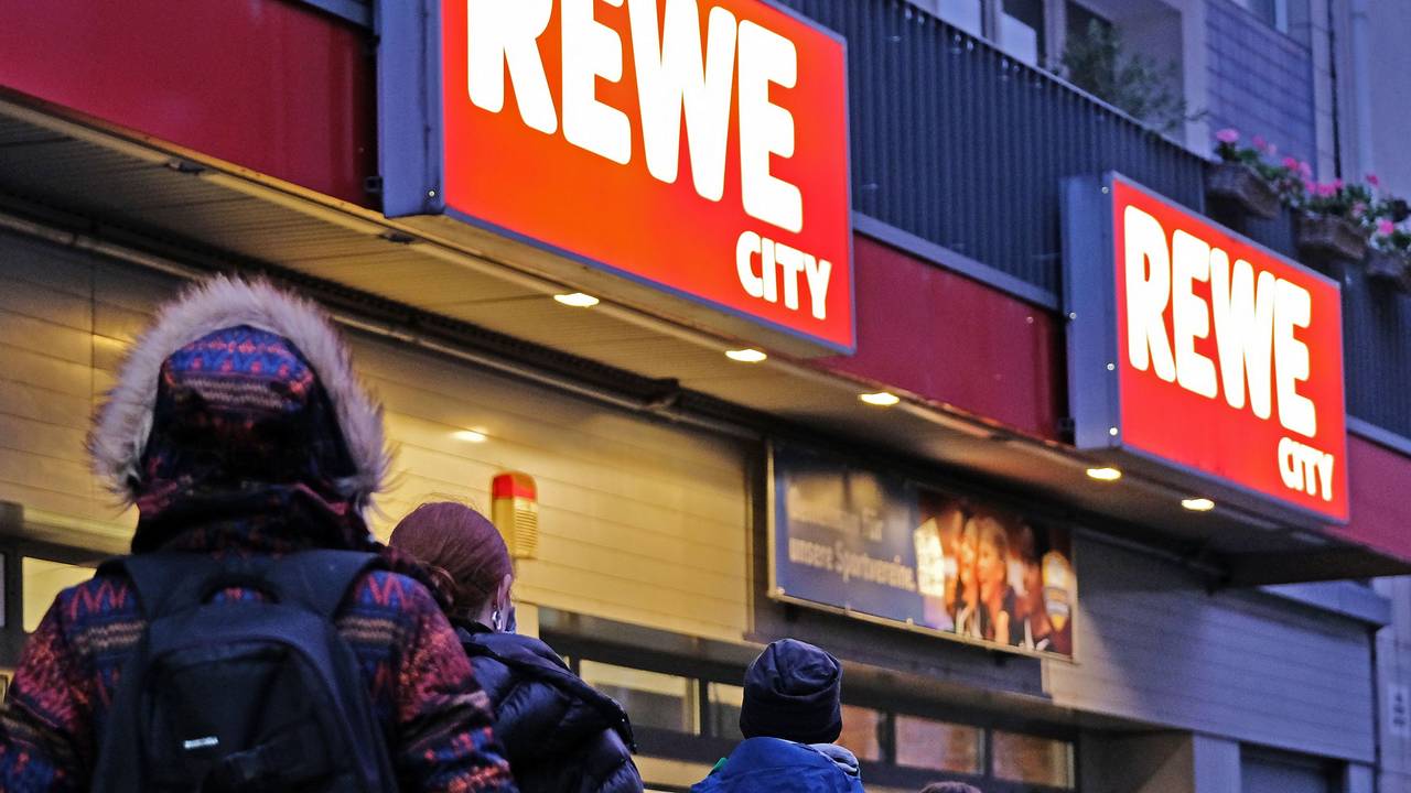 Kundinnen und Kunden vor einem REWE-Supermarkt.