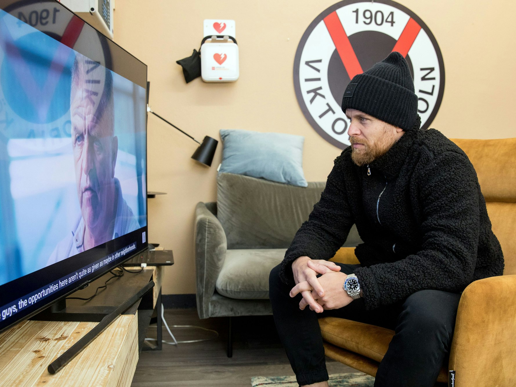 Fußballspieler Mike Wunderlich (Viktoria Köln) sitzt auf dem Sessel und schaut TV.