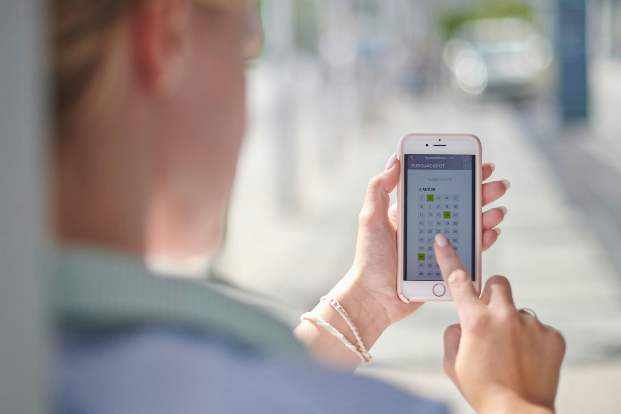 Frau tippt Lotto auf dem Smartphone.
