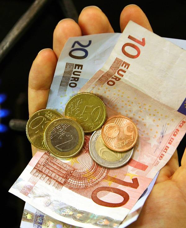 Neben einer brennenden Gasflamme an einem Herd in einer Küche im brandenburgischen Petersdorf (Oder-Spree) hält eine Frau im Oktober 2006 Geld in der Hand. Sinkende Großhandelspreise für Gas sorgen bei Verbraucherschützern für große Erwartungen.