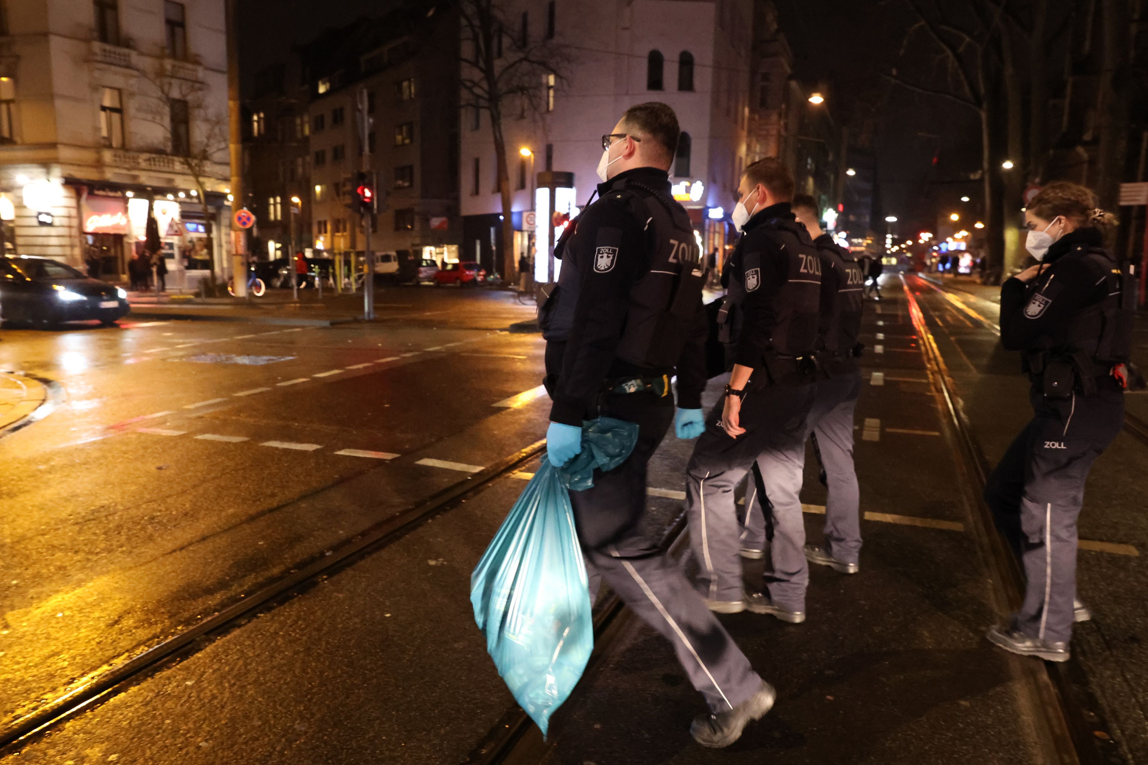 Einsatzkräfte des Zolls gehen mit sichergestelltem Material über eine Straße in Köln.