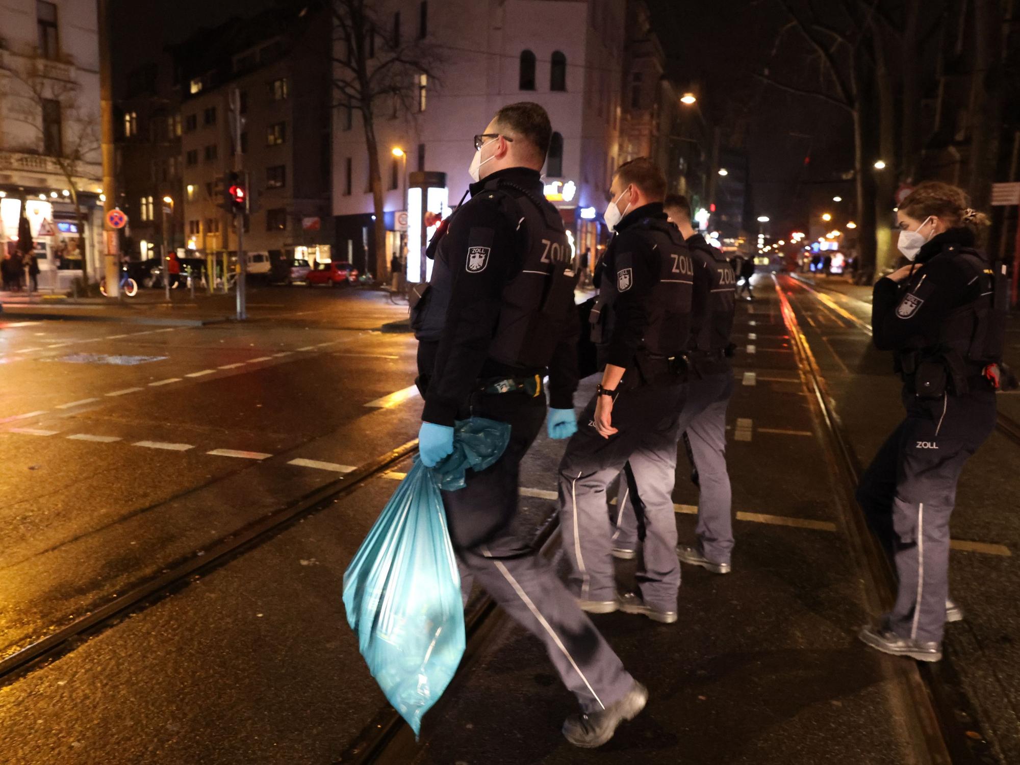 Einsatzkräfte des Zolls gehen mit sichergestelltem Material über eine Straße in Köln.