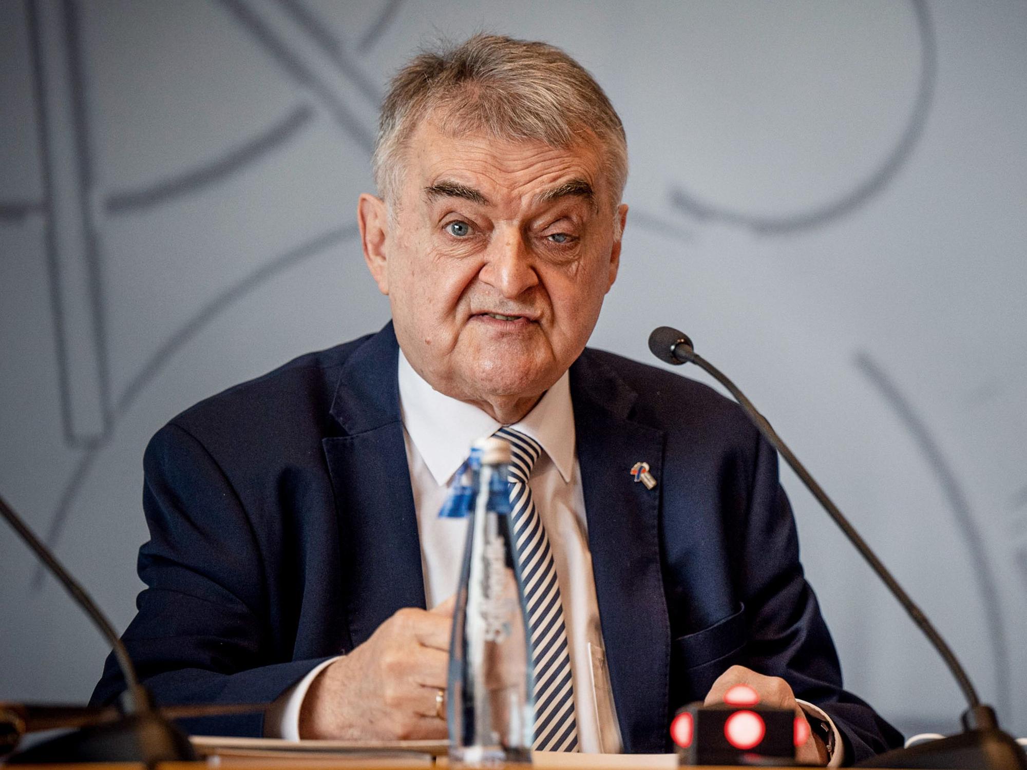 Herbert Reul sitzt vor einem Mikrofon und gibt Erklärungen bei einer Pressekonferenz ab.