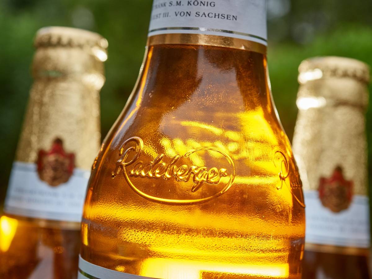 Das Foto aus dem Jahr 2018 zeigt eine volle Radeberger-Bierflasche. Im Hintergrund stehen zwei weitere Flaschen.