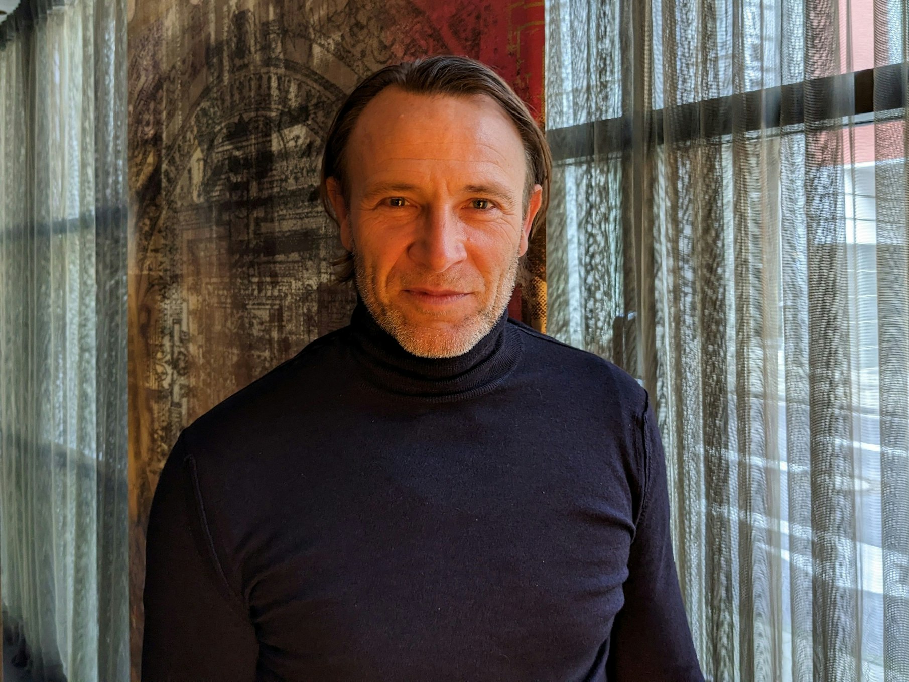 Bernhard Bettermann steht vor einem Fenster im Savoy Hotel in Köln.