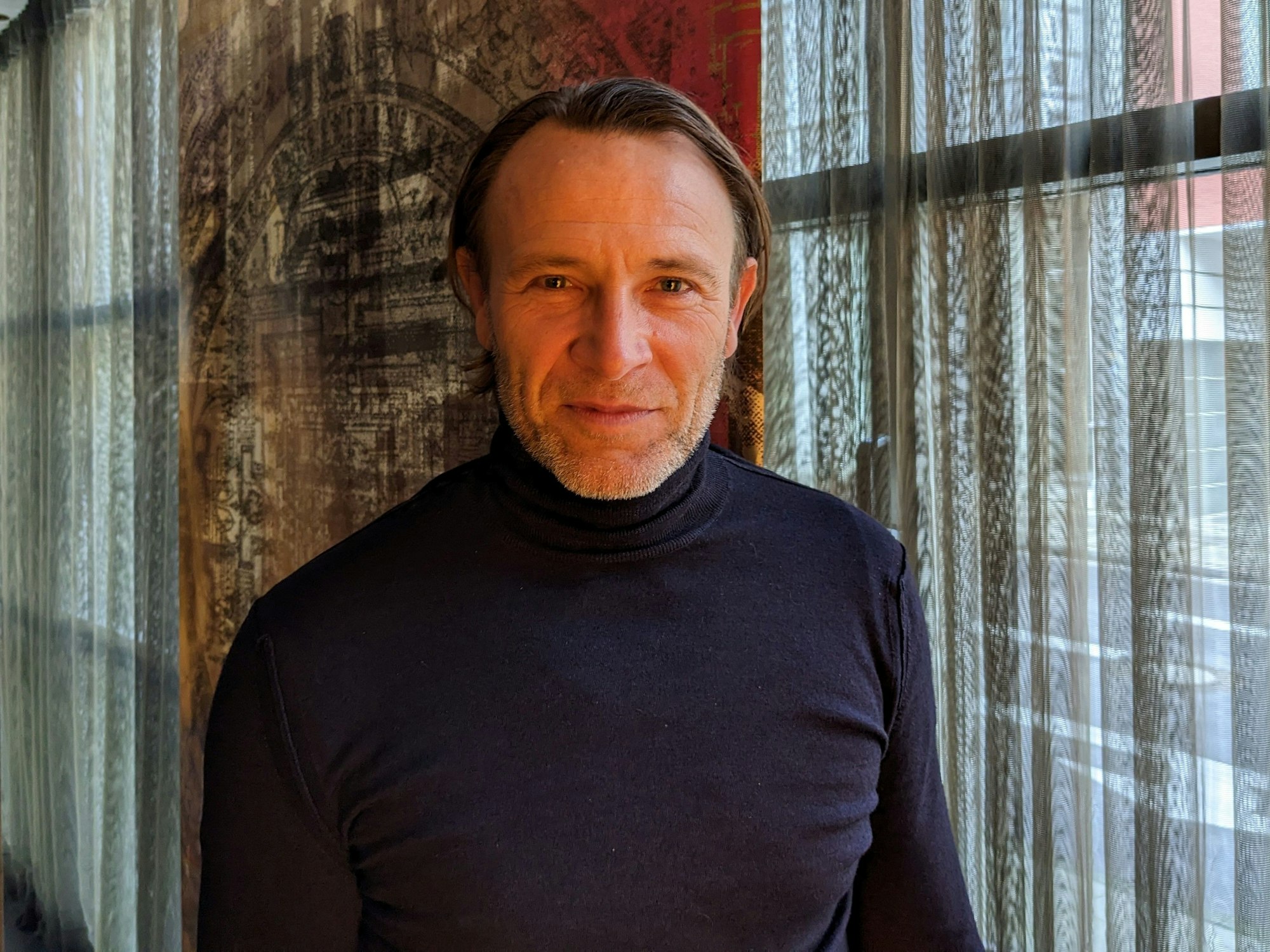 Bernhard Bettermann steht vor einem Fenster im Savoy Hotel in Köln.