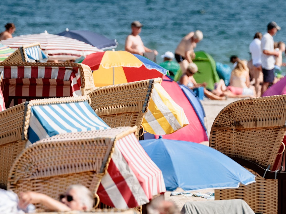 Das undatierte Symbolfoto zeigt Badegäste am Meer und Strandkörbe mit bunten Markisen.