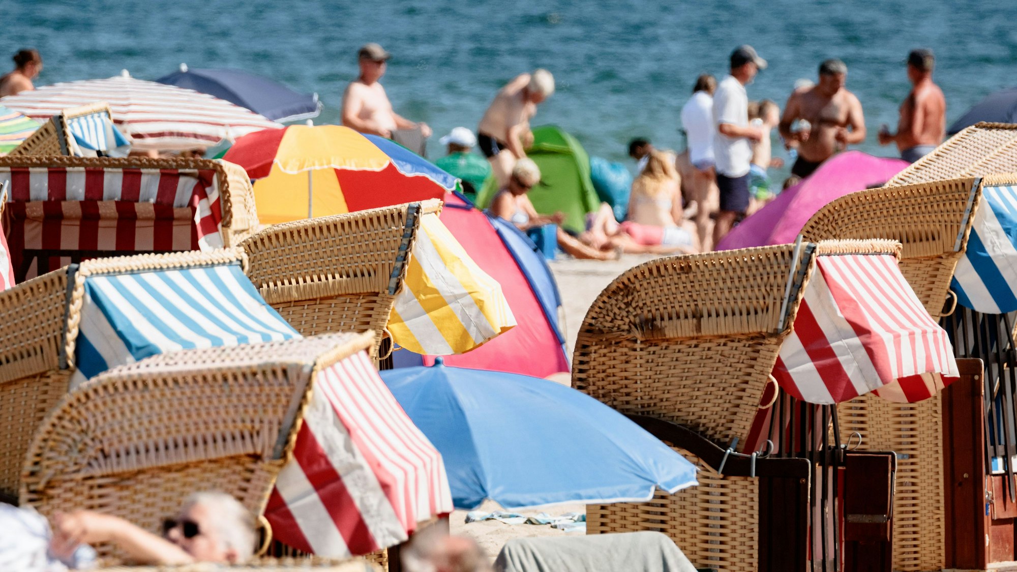 Das undatierte Symbolfoto zeigt Badegäste am Meer und Strandkörbe mit bunten Markisen.
