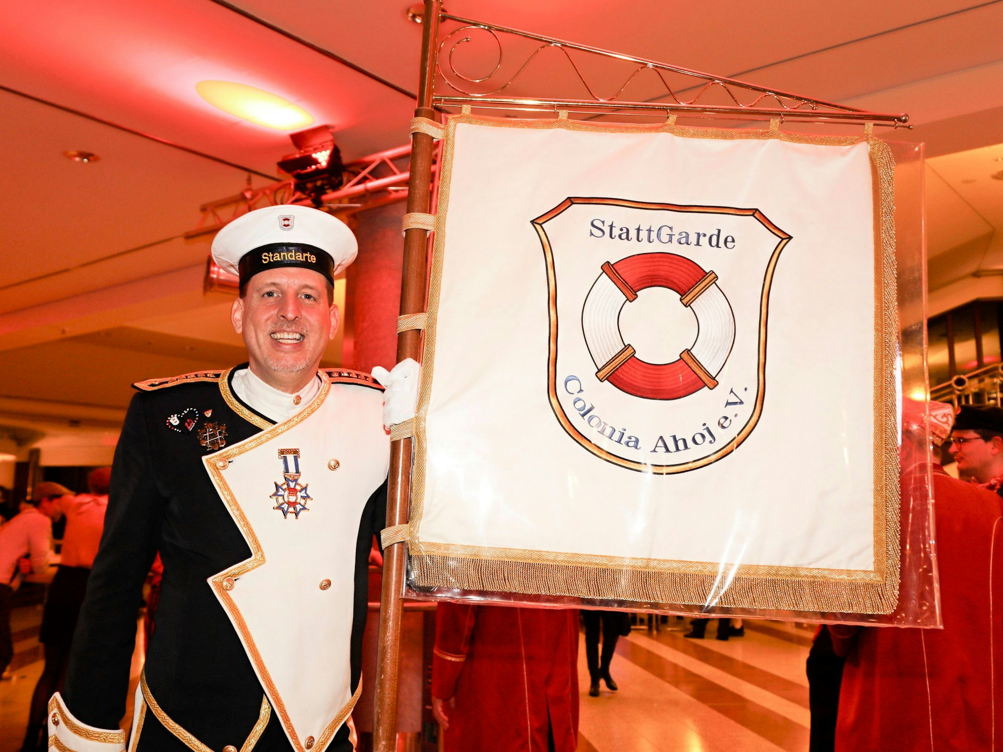 André Schulze Isfort steht in einem Kostüm neben einer Fahne.