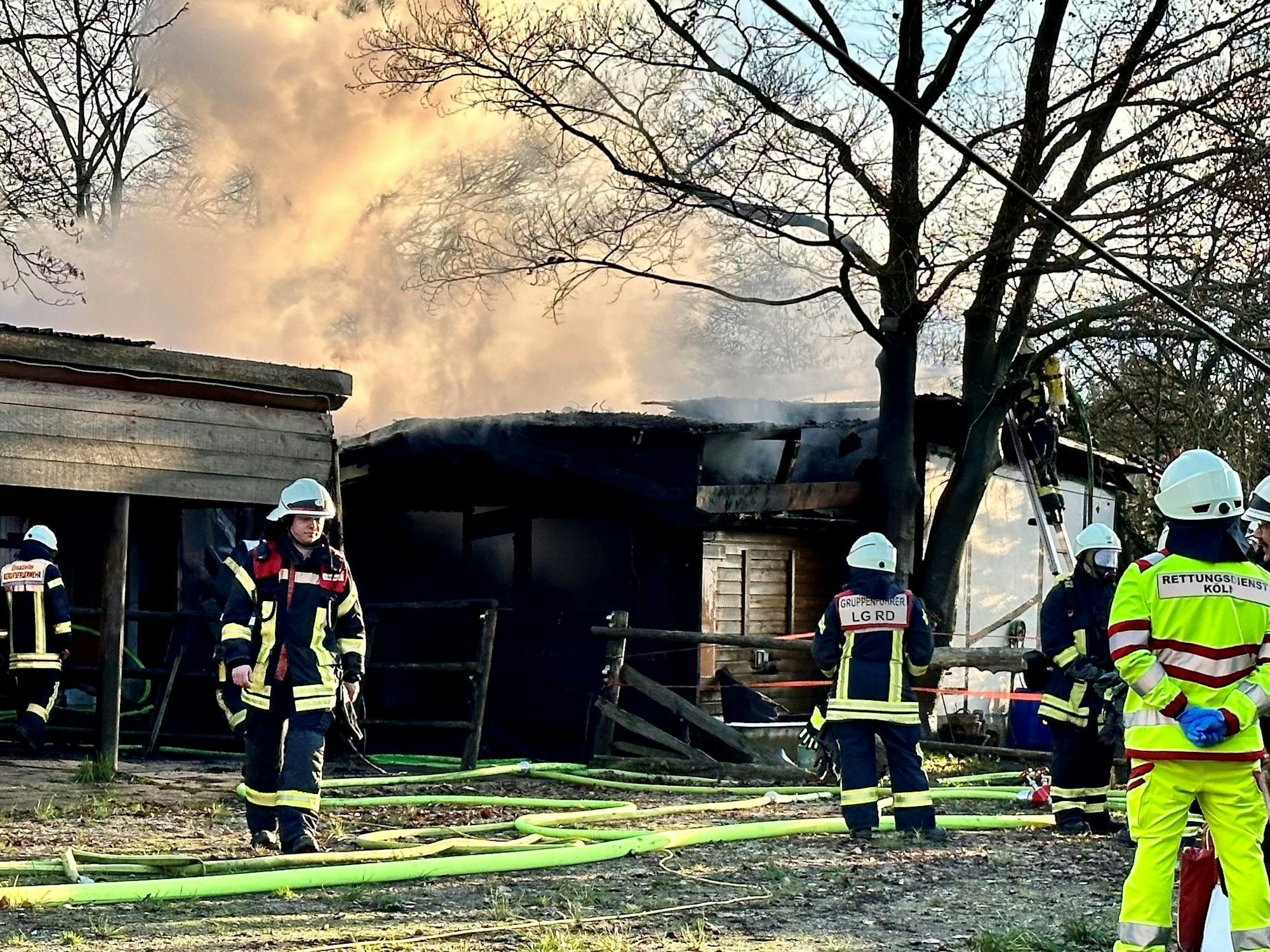 Feuerwehrleute sind bei einem Brand in einer Laube in Köln-Rodenkirchen im Einsatz.