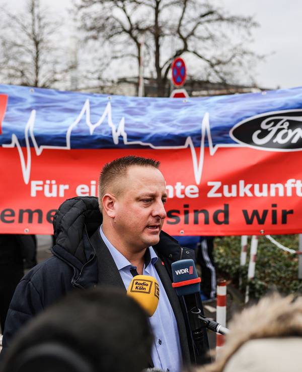 Benjamin Gruschka, Betriebsratsvorsitzender von Ford, spricht vor dem Werksgelände zu Journalisten.