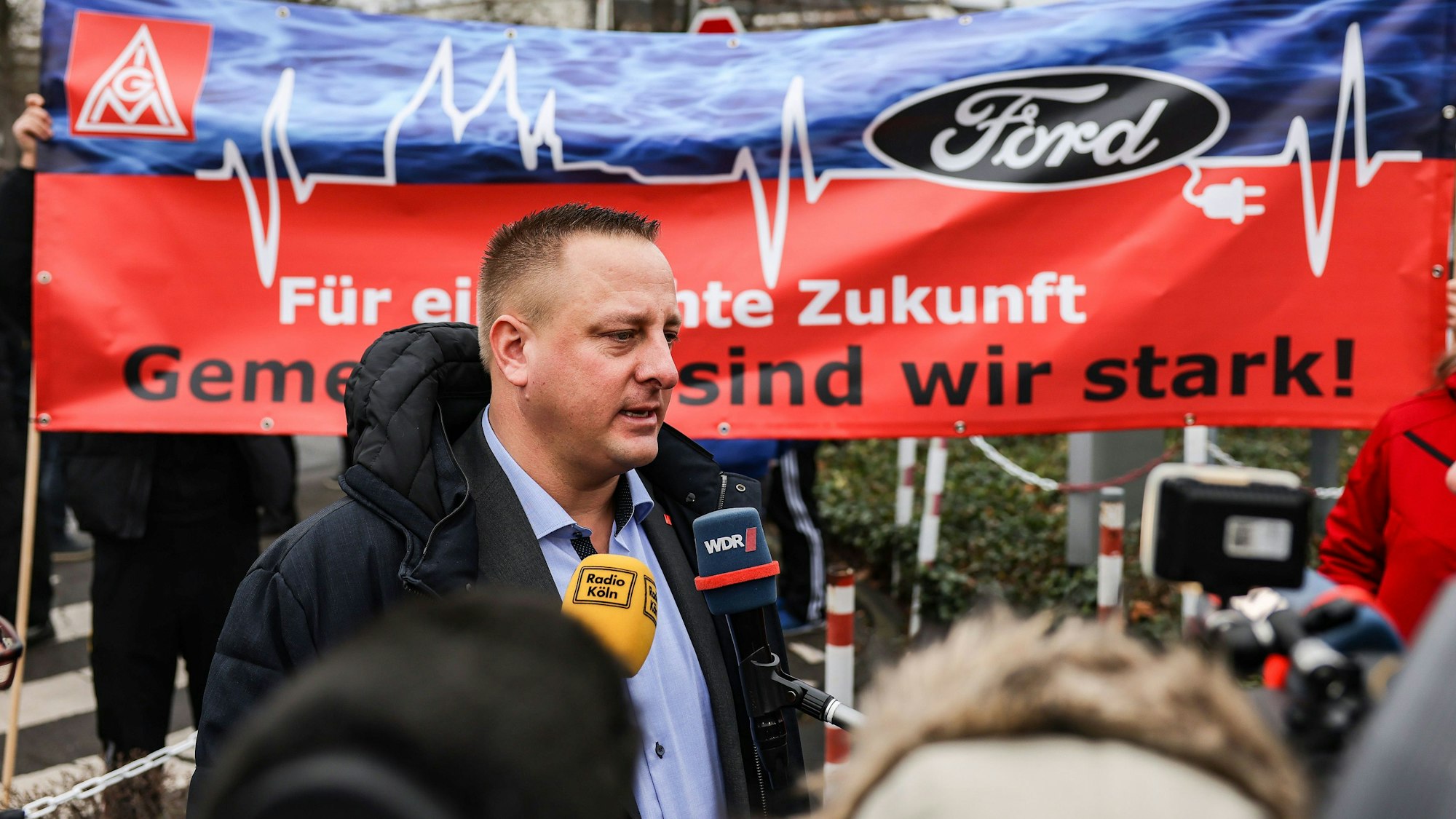 Benjamin Gruschka, Betriebsratsvorsitzender von Ford, spricht vor dem Werksgelände zu Journalisten.