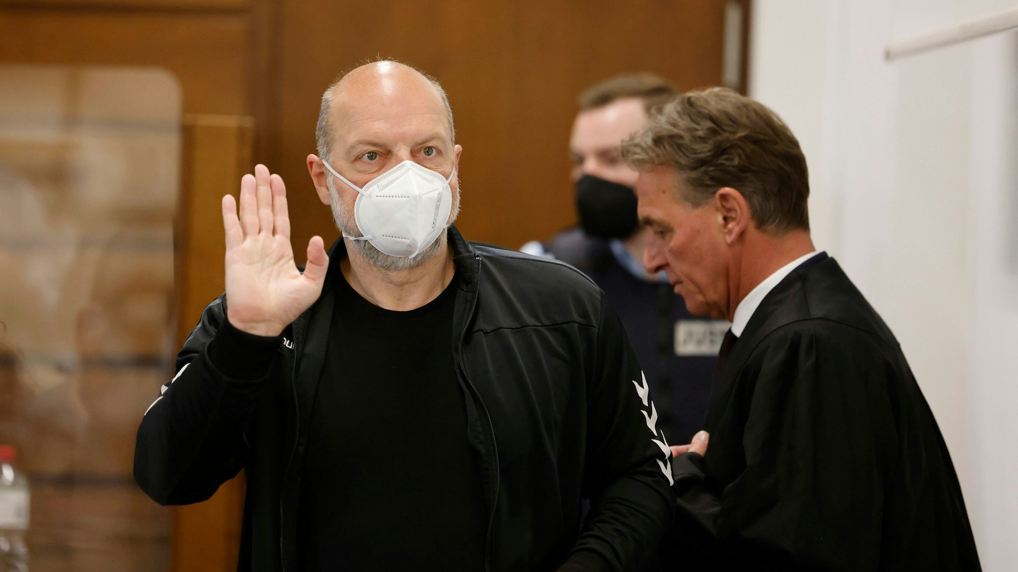 Der Angeklagte Thomas Drach betritt den Gerichtssaal und winkt in Richtung Publikum.