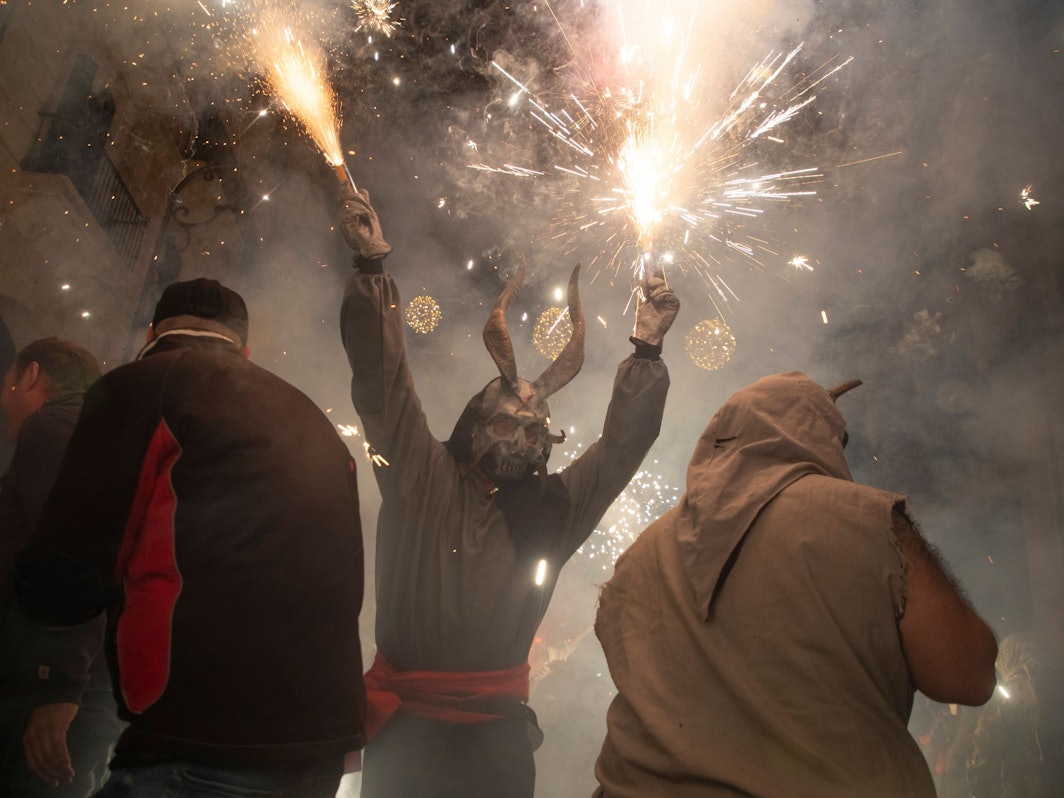 Ein als Dämon verkleideter Mann, der ein Feuerwerk in der Hand hält, läuft während des traditionellen Correfoc zum Abschluss des alljährlichen Stadtfestes zu Ehren des Stadtheiligen Sant Sebastià (Heiliger Sebastian) unter den Menschen.