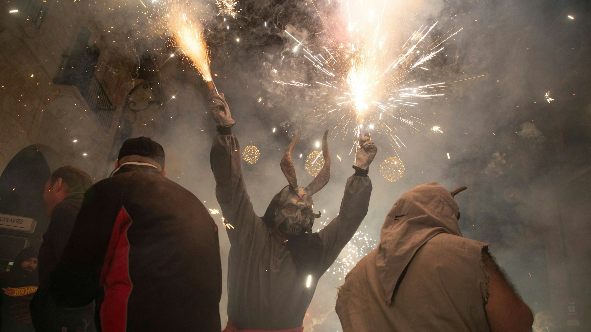 Ein als Dämon verkleideter Mann, der ein Feuerwerk in der Hand hält, läuft während des traditionellen Correfoc zum Abschluss des alljährlichen Stadtfestes zu Ehren des Stadtheiligen Sant Sebastià (Heiliger Sebastian) unter den Menschen.