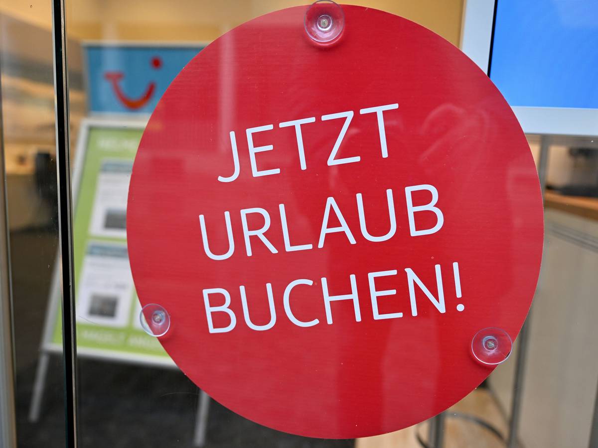 Das undatierte Symbolfoto zeigt ein Schaufenster mit einem runden roten Aufkleber und den Worten „Jetzt Urlaub buchen!“.