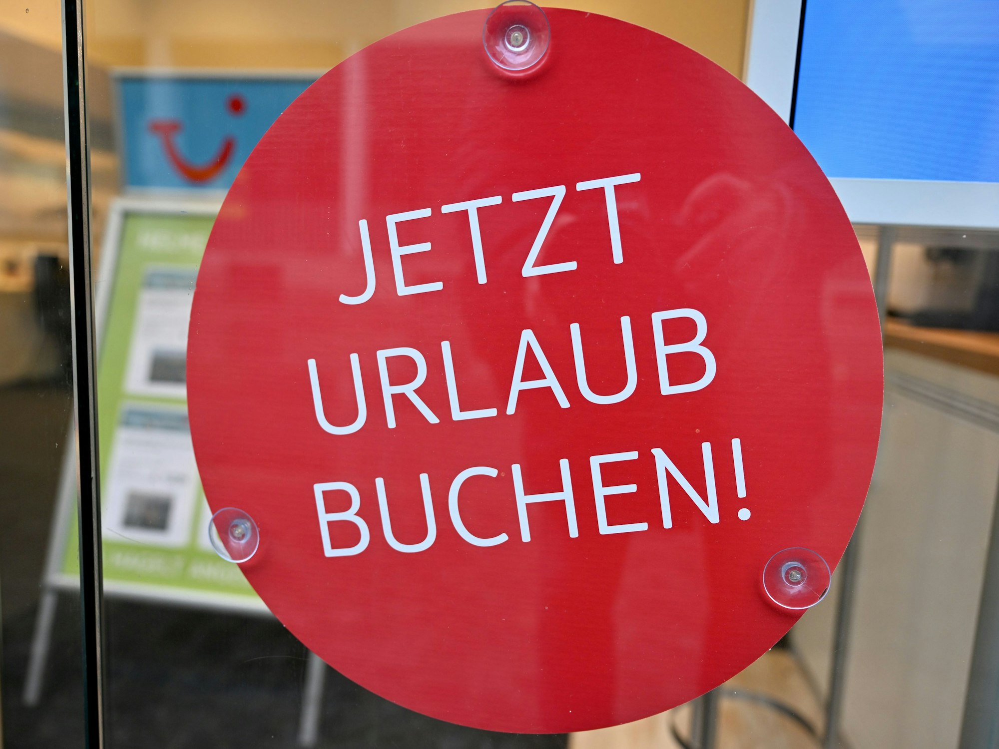 Das undatierte Symbolfoto zeigt ein Schaufenster mit einem runden roten Aufkleber und den Worten „Jetzt Urlaub buchen!“.