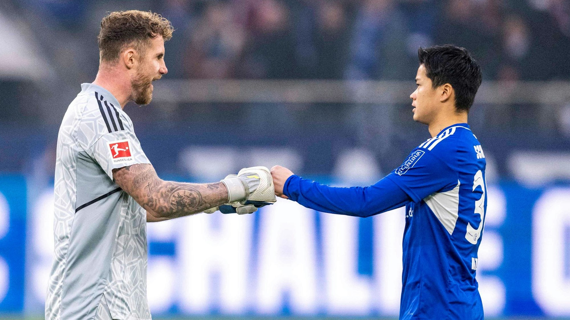 Ralf Fährmann klatscht beim Spiel gegen den 1. FC Köln mit Maya Yoshida ab.