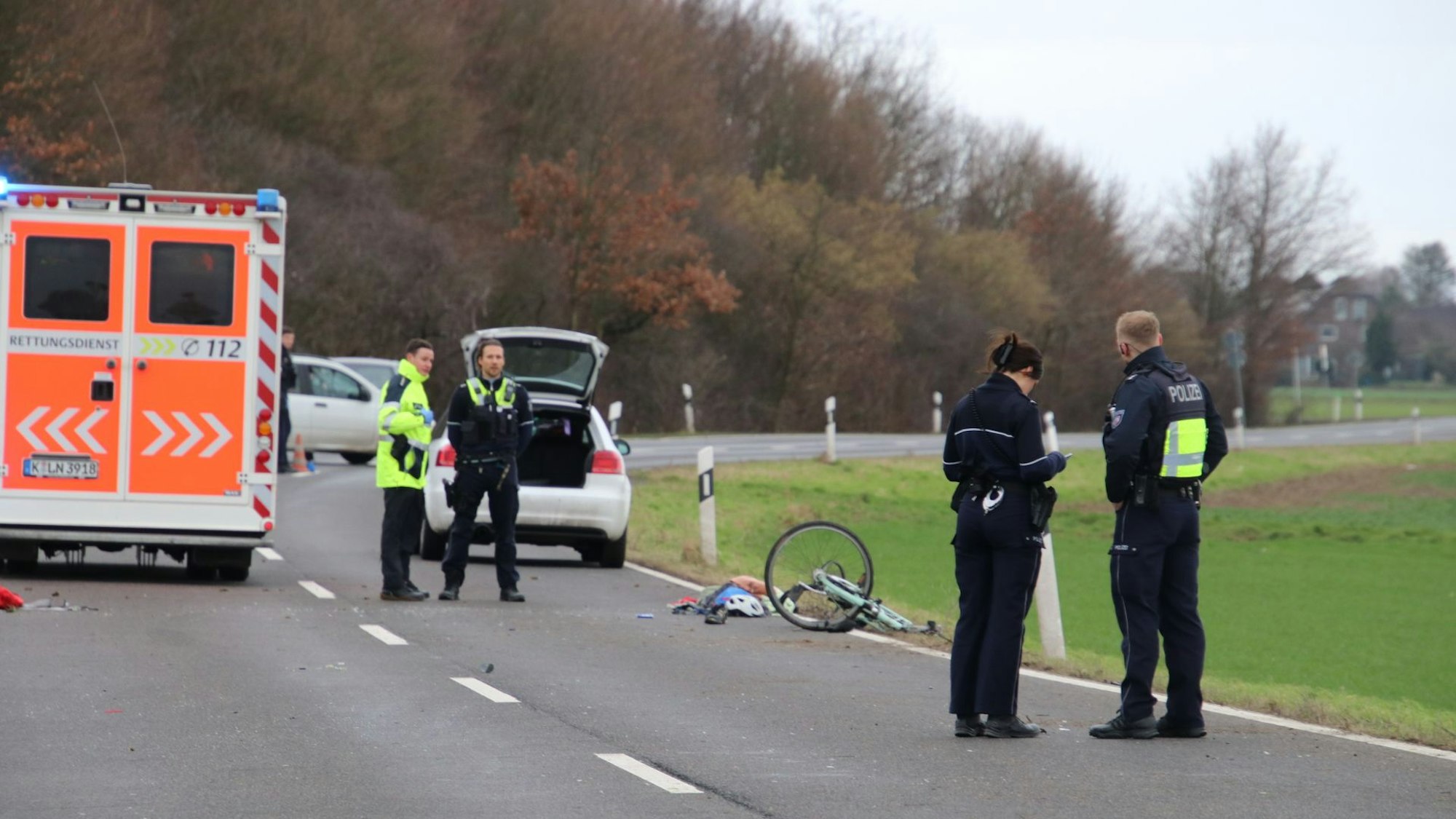 Ein beschädigtes Fahrrad liegt auf der Fahrbahn, ein paar Meter weiter stehen Einsatzkräfte sowie ein Rettungswagen.