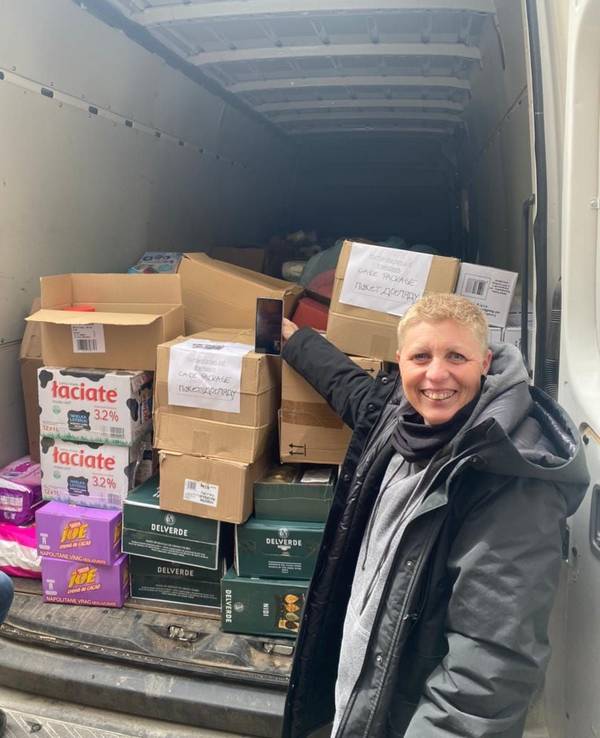 Eine Frau steht neben einem mit Kisten beladenen Transporter.
