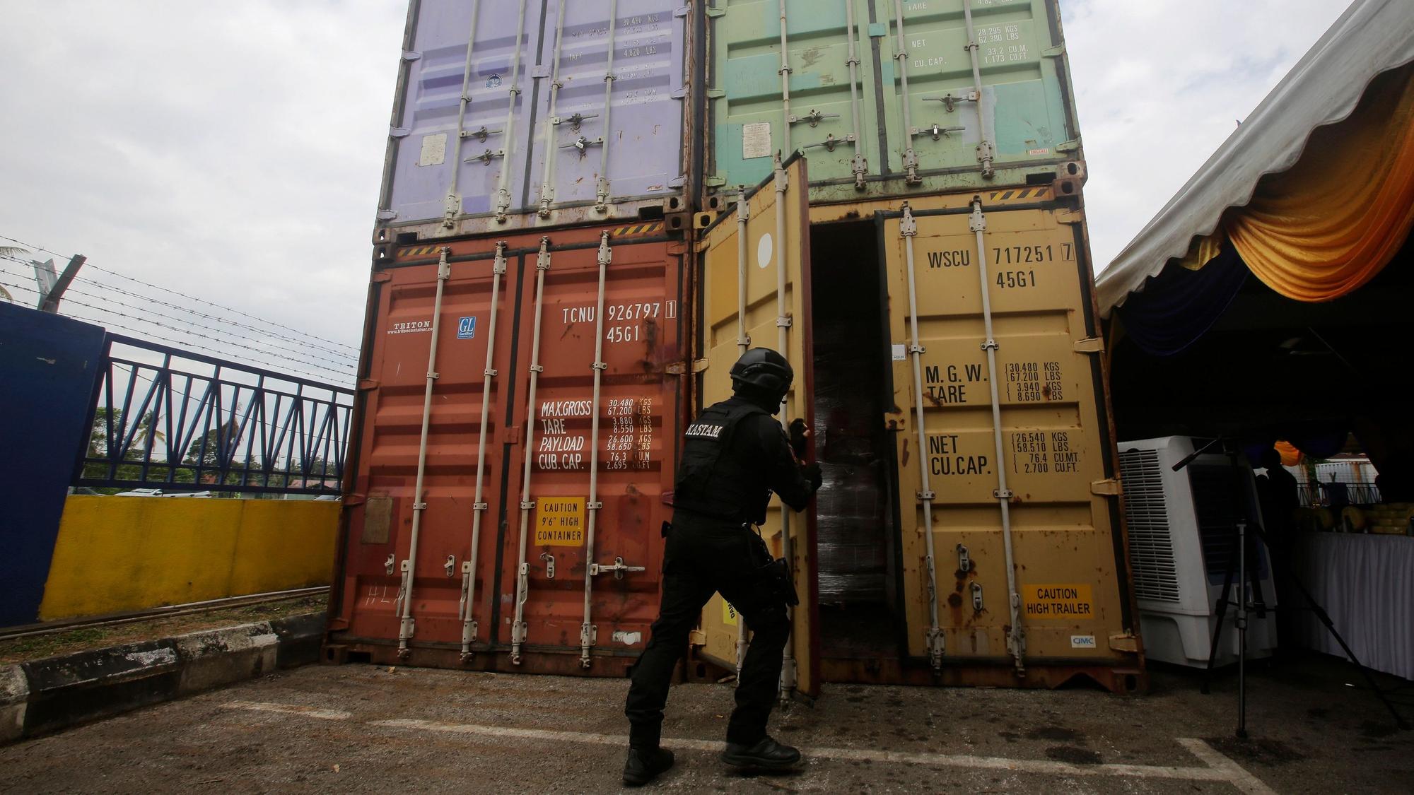 Das undatierte Symbolfoto zeigt einen schwarz gekleideten Polizisten, der eine Containertür schließt.