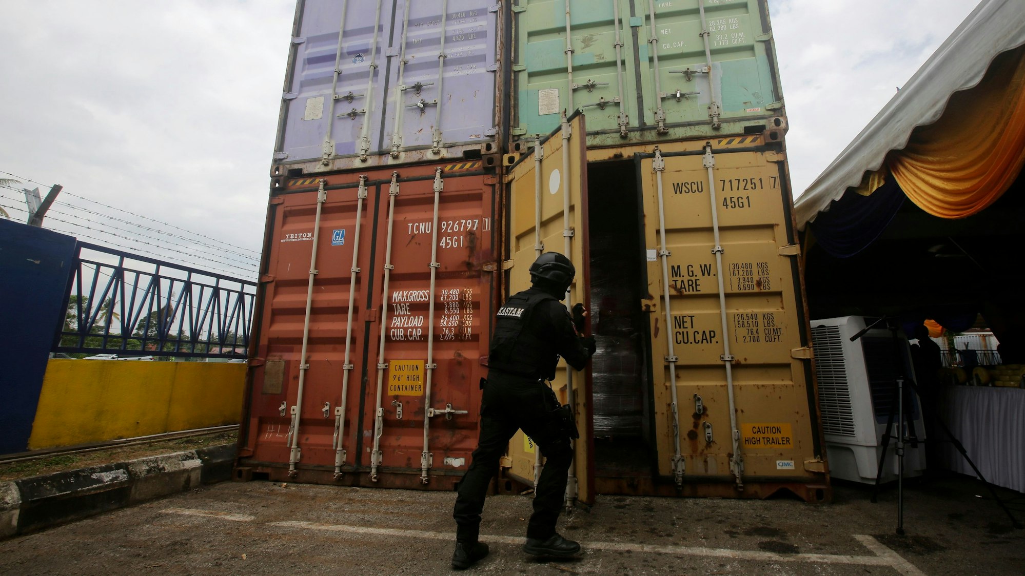 Das undatierte Symbolfoto zeigt einen schwarz gekleideten Polizisten, der eine Containertür schließt.