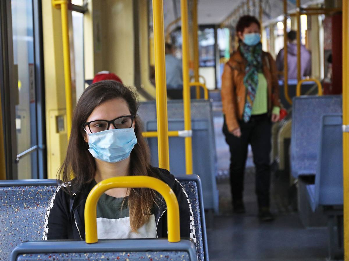 Eine Frau sitzt mit einer Schutzmaske in einer Straßenbahn.
