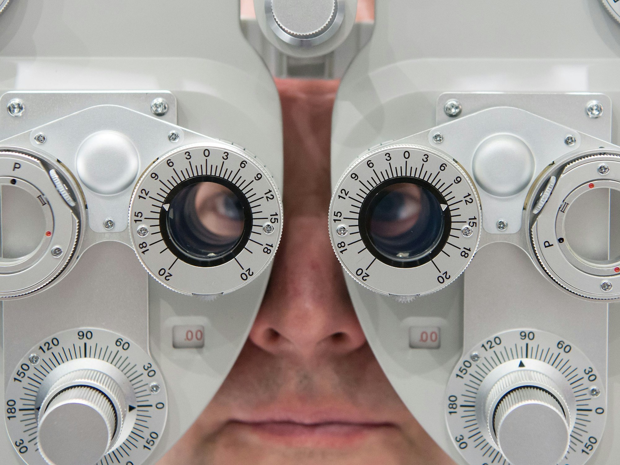 Ein Mann, hier im Januar 2016 in München, sitzt auf der Optik- und Brillenmesse Opti hinter einem Phoropter.