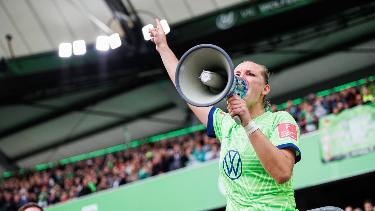 Alexandra Popp vom VfL Wolfsburg steht auf dem Zaun und feiert mit Wolfsburger Fans nach Spielende und spricht durch ein Megaphon der Fans.