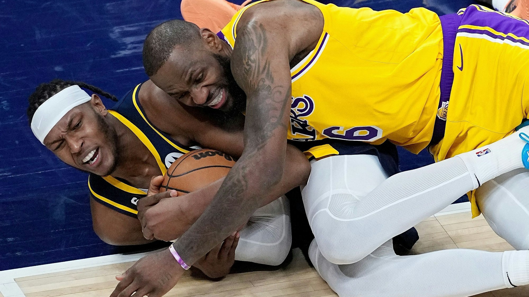 Myles Turner von den Indiana Pacers und LeBron James von den Los Angeles Lakers kämpfen am Boden liegend um den Ball.