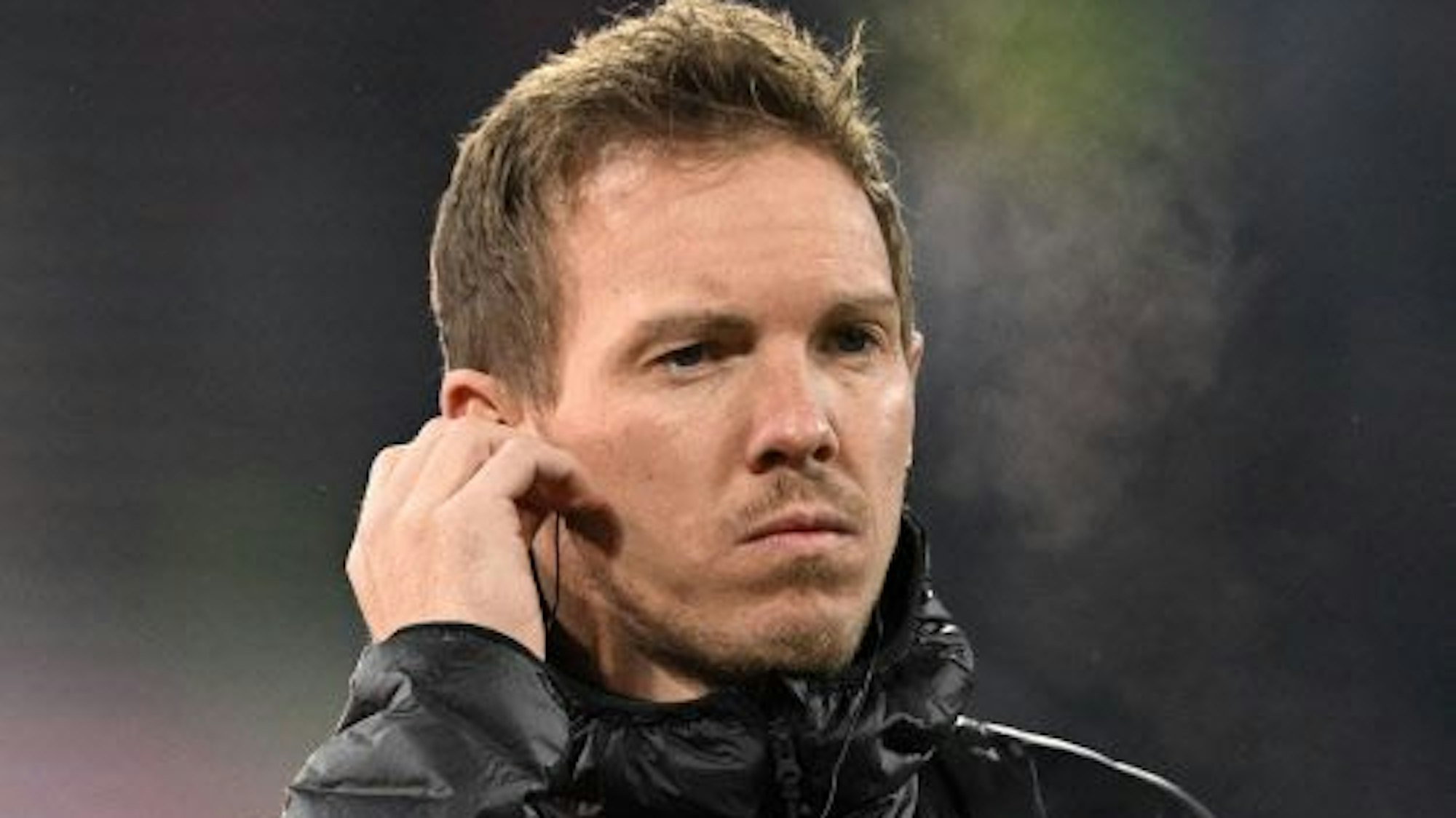 Julian Nagelsmann steht vor dem Spiel gegen Eintracht Frankfurt in der Kälte, er hat einen Knopf im Ohr.