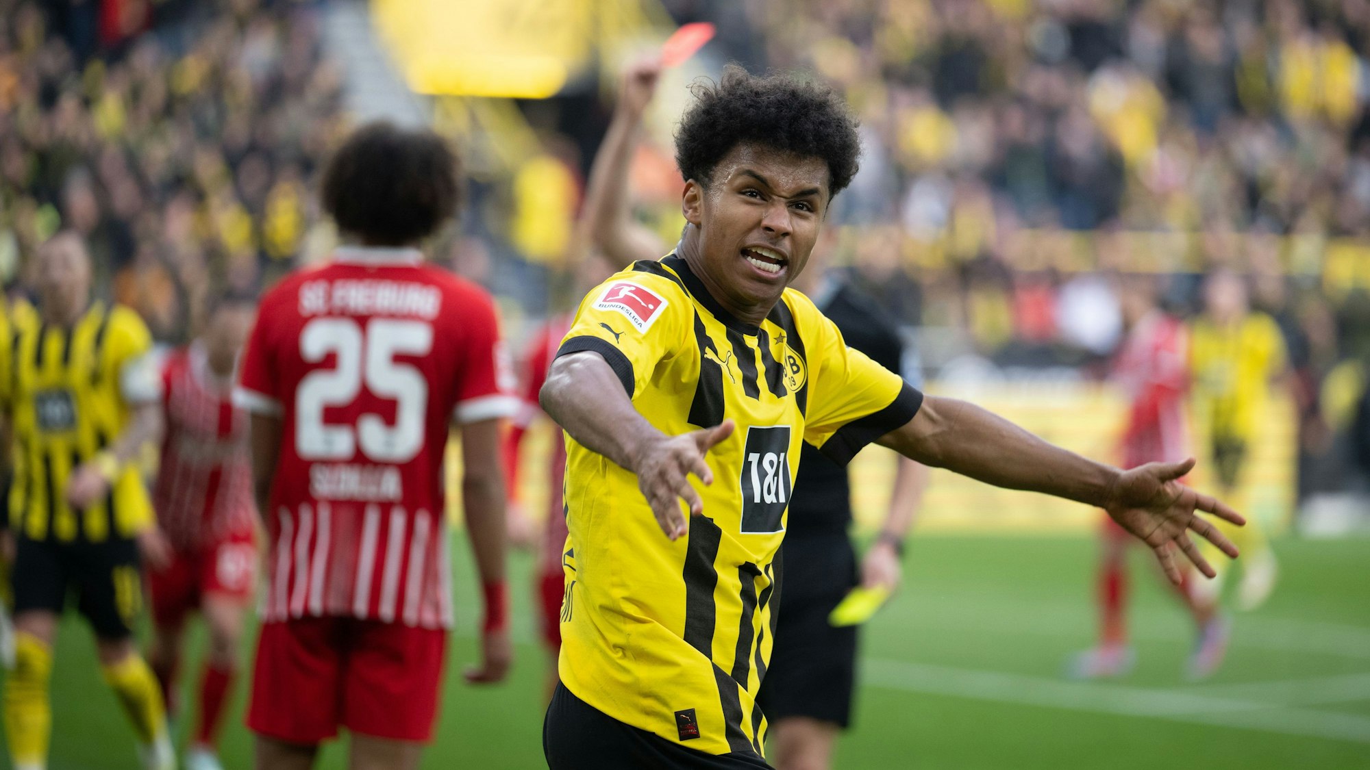 Dortmunds Karim Adeyemi jubelt, während Kiliann Sildillia (l) von Freiburg die Rote Karte sieht.