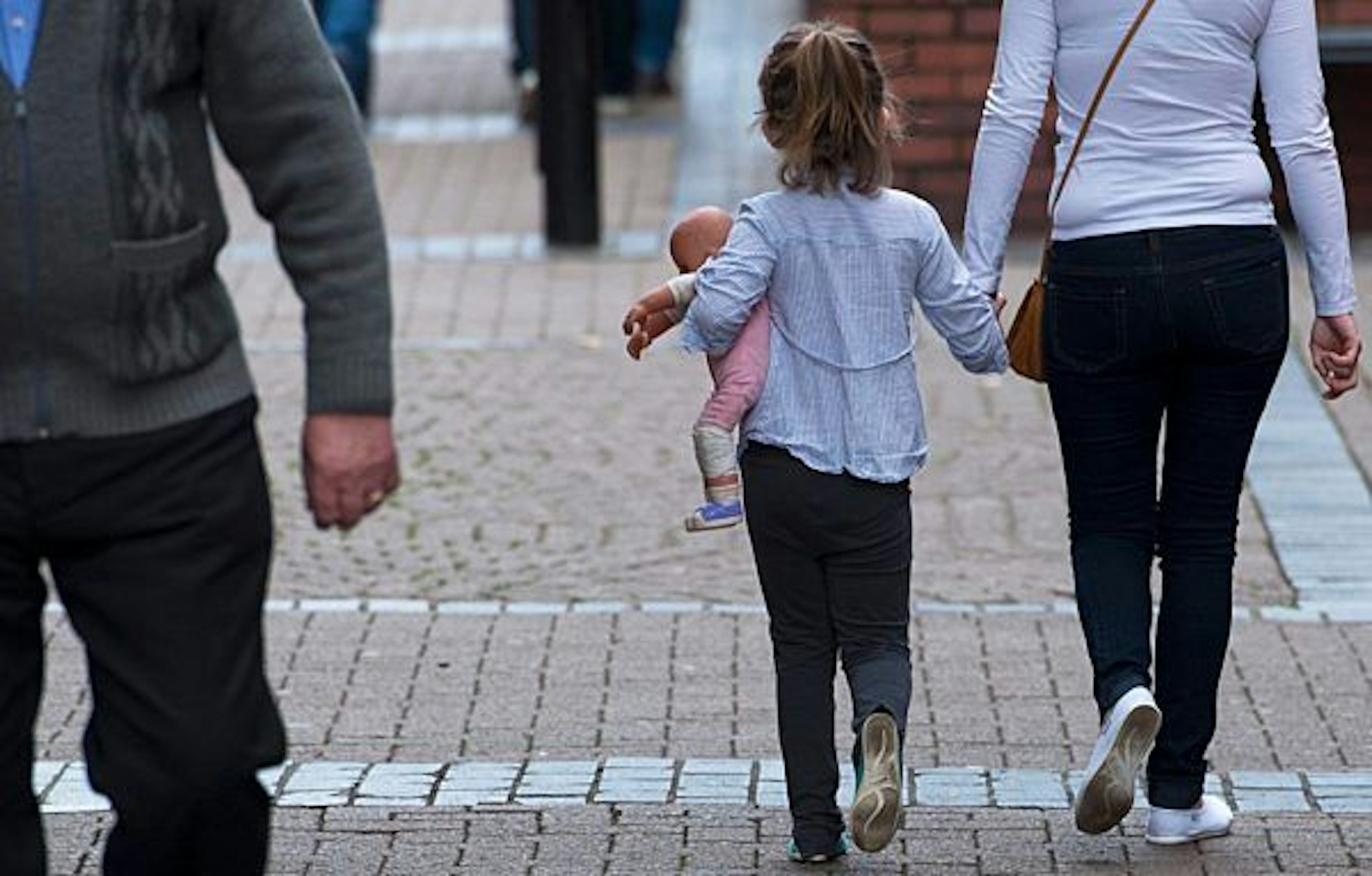 A young girl holds a doll as she is walking hand in hand with a woman in Rotherham, Yorkshire, Britain, 27 August 2014.