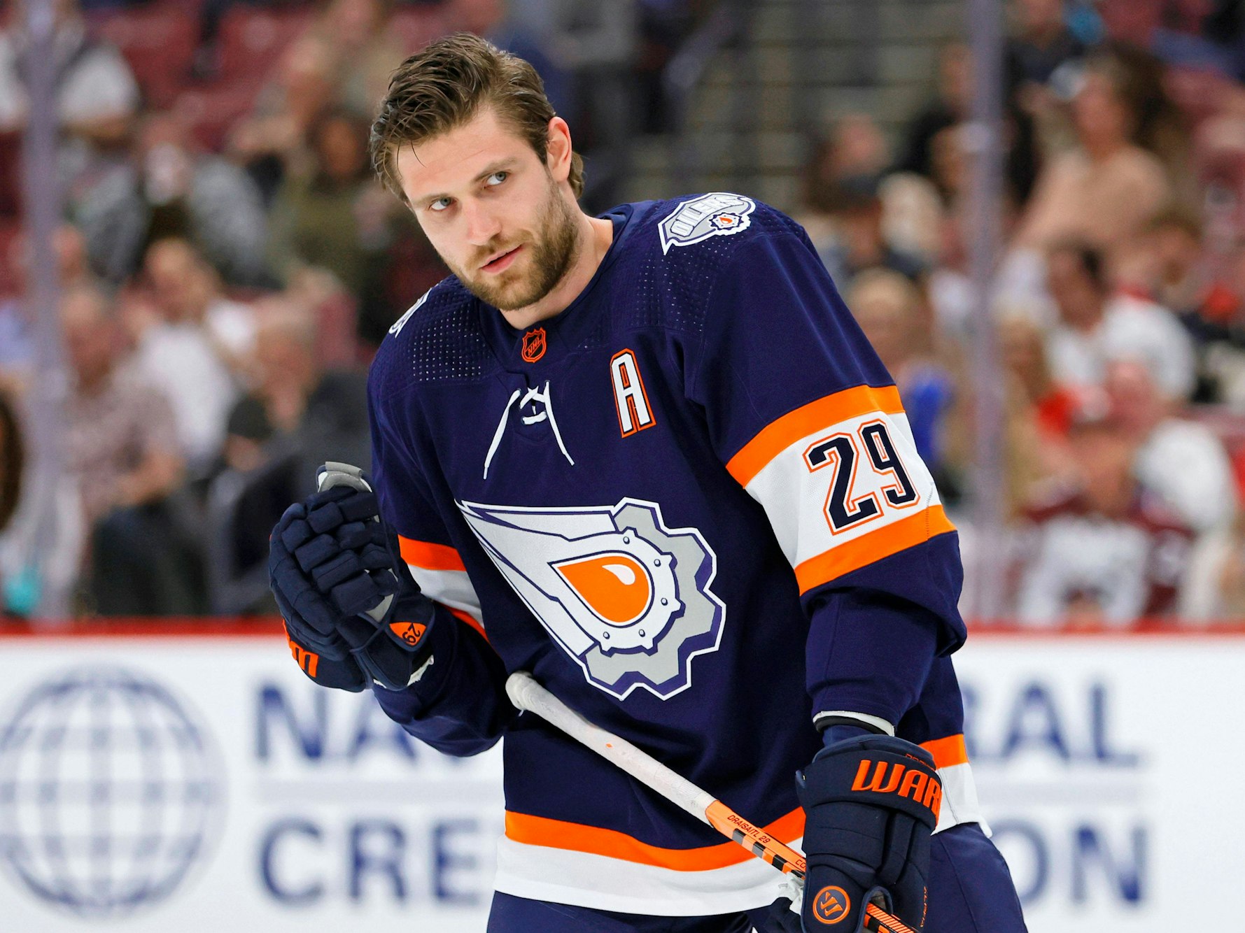 Leon Draisaitl steht ohne Helm auf dem Eis.