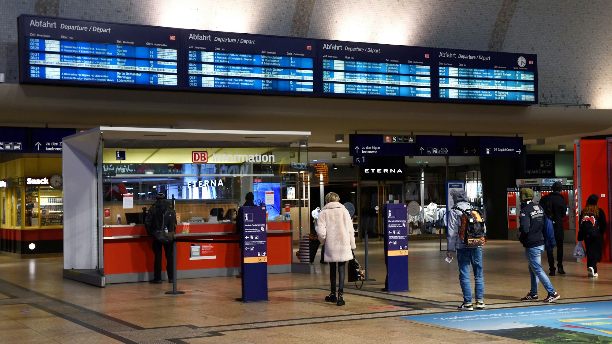 Menschen stehen vor dem Service-Point am Haupteingang des Kölner Hauptbahnhofs und warten.