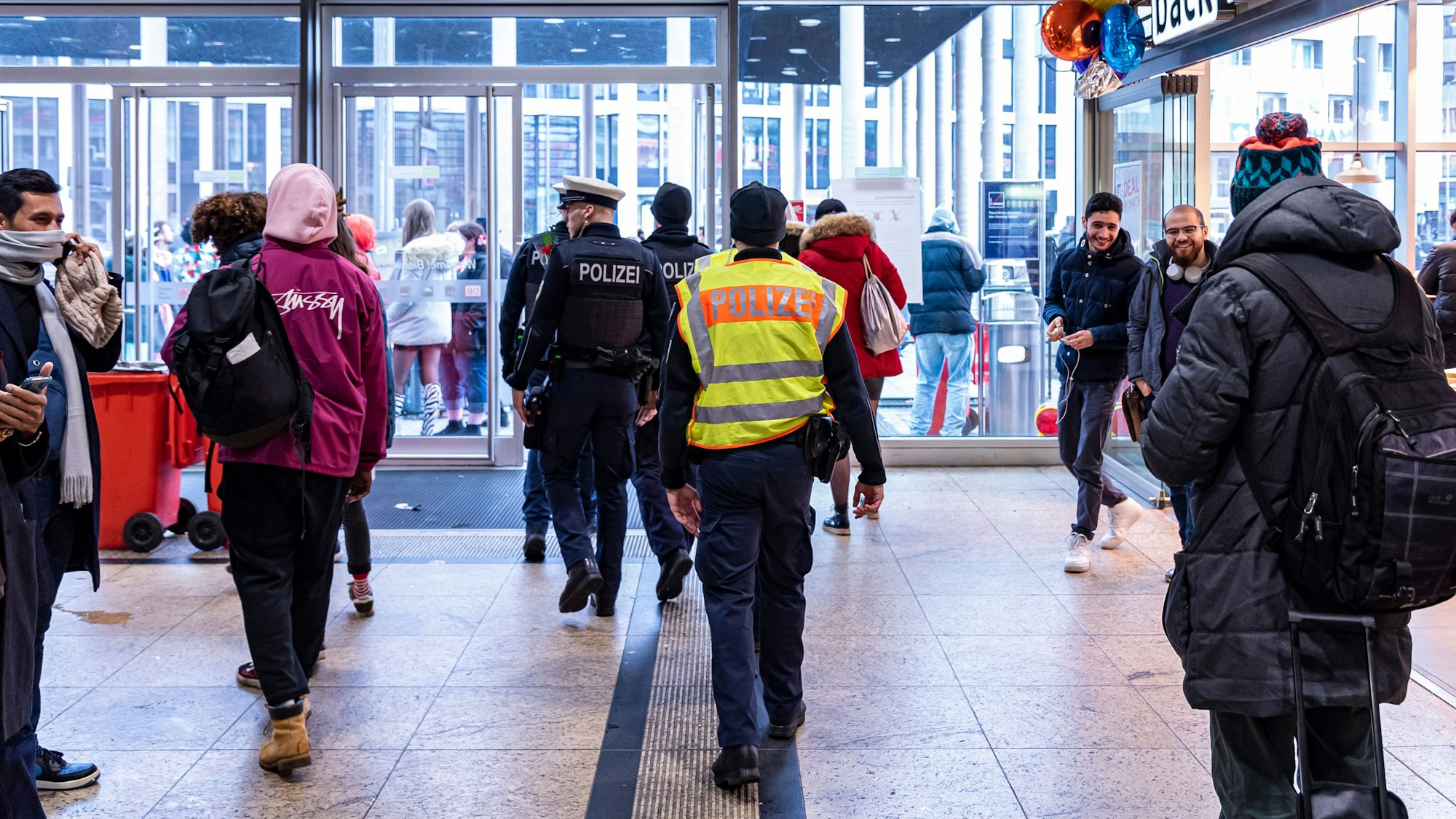 Polizisten gehen durch den Kölner Hauptbahnhof in Richtung Ausgang.