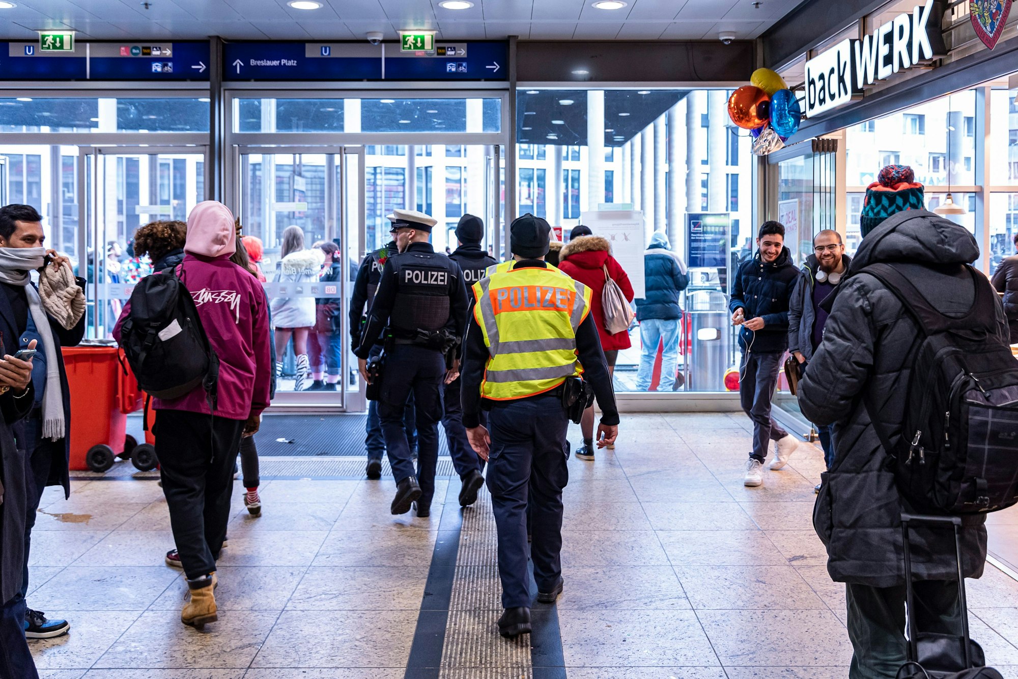 Polizisten gehen durch den Kölner Hauptbahnhof in Richtung Ausgang.