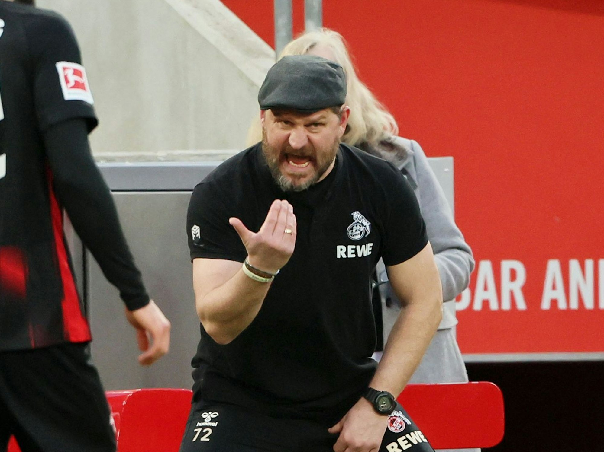 Trainer Steffen Baumgart (1. FC Köln) brüllt mit Schiebermütze an der Seitenlinie.