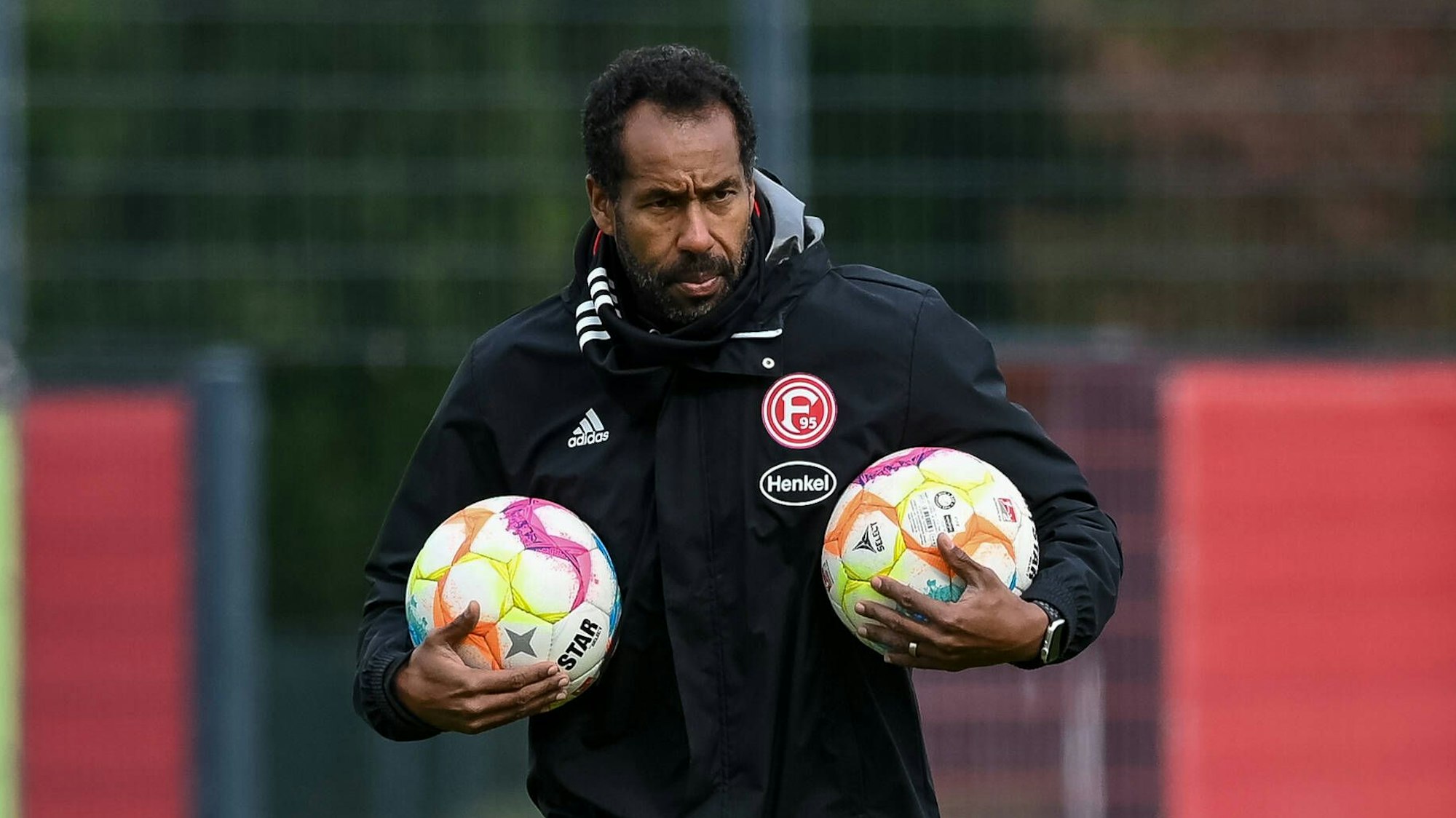 Düsseldorfs Trainer Daniel Thioune trägt zwei Bälle über den Trainingsplatz.