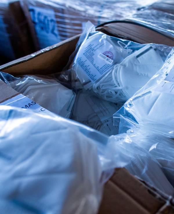 Ein offener Karton mit Mundschutzmasken steht im zentralen Materiallager für Schutzausrüstung und Hygienemittel.